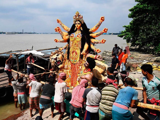 Hindus verladen eine Statue der Gttin Durga auf einen Kahn.   | Foto: AFP