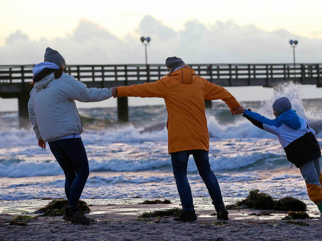 Spaziergnger halten sich bei Sturm an der Ostsee am Strand von Wustrow (Mecklenburg-Vorpommern) gegenseitig fest.