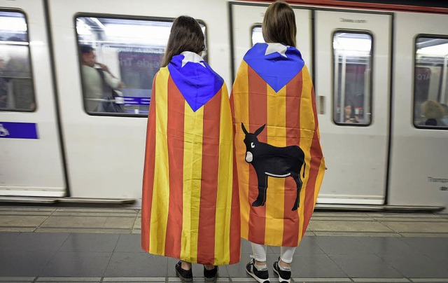 Die katalanischen Farben um die Schult...Frauen an einem Bahnsteig in Barcelona  | Foto: dpa