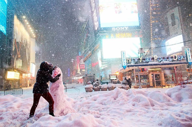 Eine Frau dekoriert in New York einen Schneemann auf dem Times Square.  | Foto: AFP
