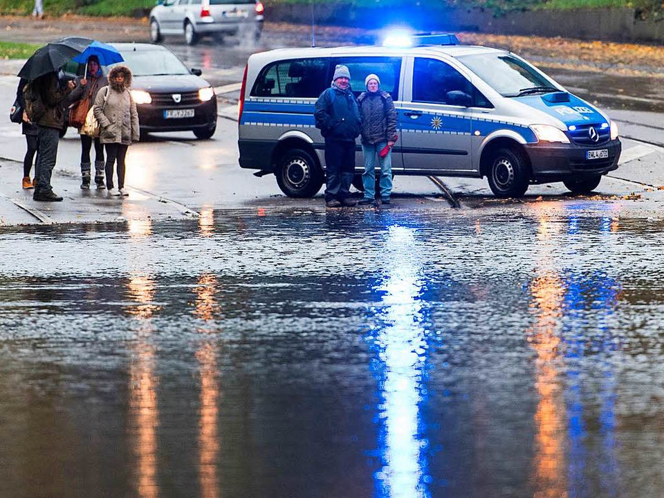 Ein Polizeifahrzeug steht in Freiburg vor einer überfluteten Straße.  | Foto: dpa