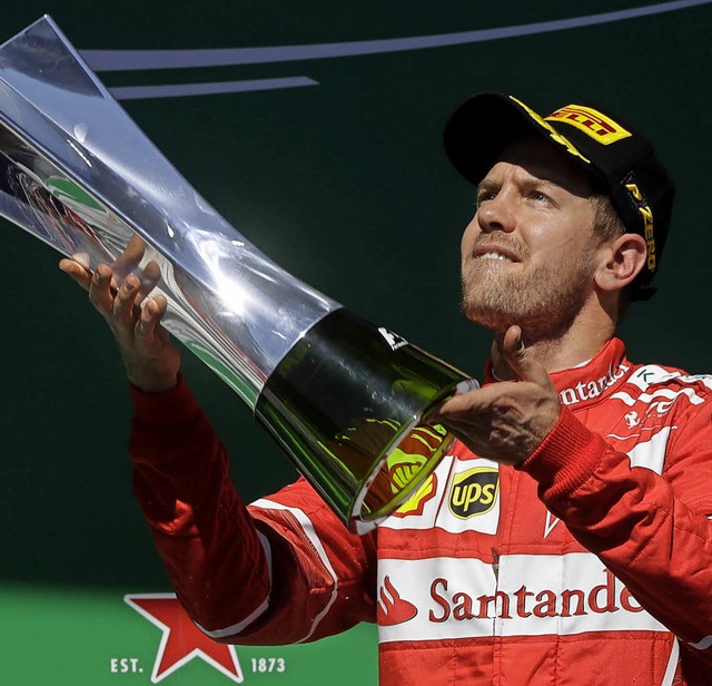 Sebastian Vettel stemmt den Siegerpokal in die Hhe.   | Foto: dpa
