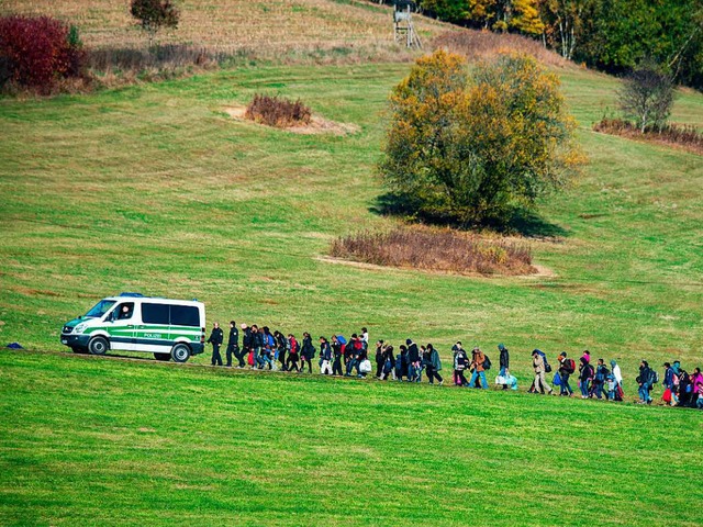 Schutzsuchende gehen im Oktober 2015  ...nter einem Fahrzeug der Bundespolizei.  | Foto: Armin Weigel