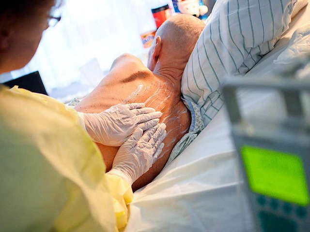Eine Krankenpflegerin behandelt auf einer Palliativstation einen Patienten.   | Foto: dpa