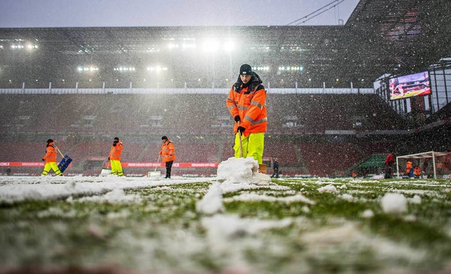 Vor dem Spiel rumen Ordner des 1. FC Kln die Schneemassen vom Rasen.  | Foto: dpa