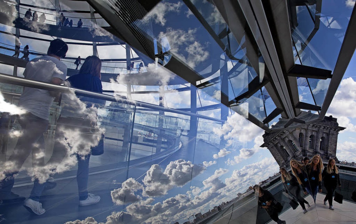 Wolken spiegeln sich in Berlin im Glas der Reichstagskuppel.   | Foto: dpa