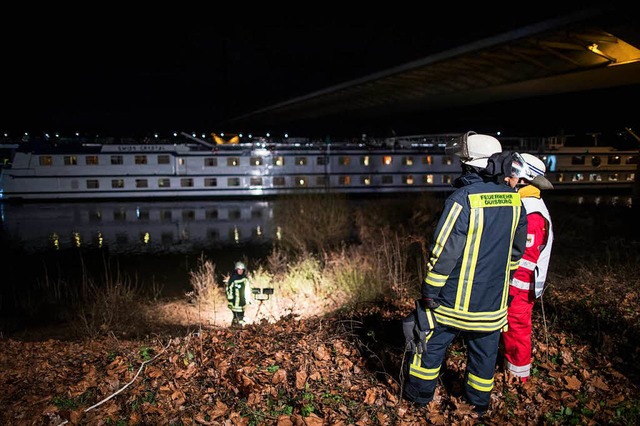 Feuerwehrleute stehen in Duisburg am Rheinufer vor dem Ausflugsschiff.  | Foto: dpa