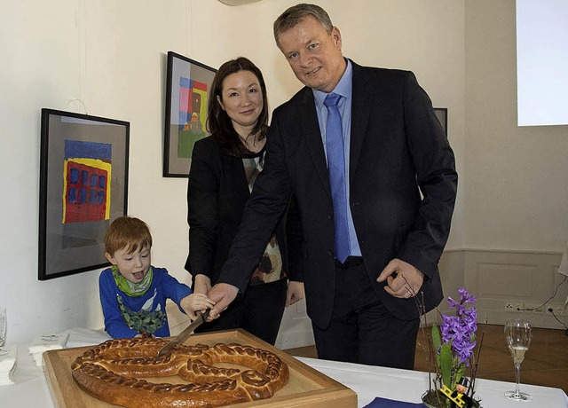 Schnitten die Neujahrsbrezel an: Brgermeister Dirk Blens, seine Frau mit Sohn.   | Foto: Volker Mnch