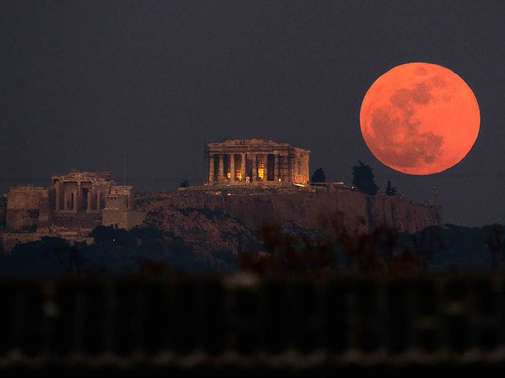 Griechenland, Athen: Der Vollmond, ein sogenannter Supermond, weil er sich besonders nah an der Erde befindet, steht blutrot leuchtend ber dem Parthenon.