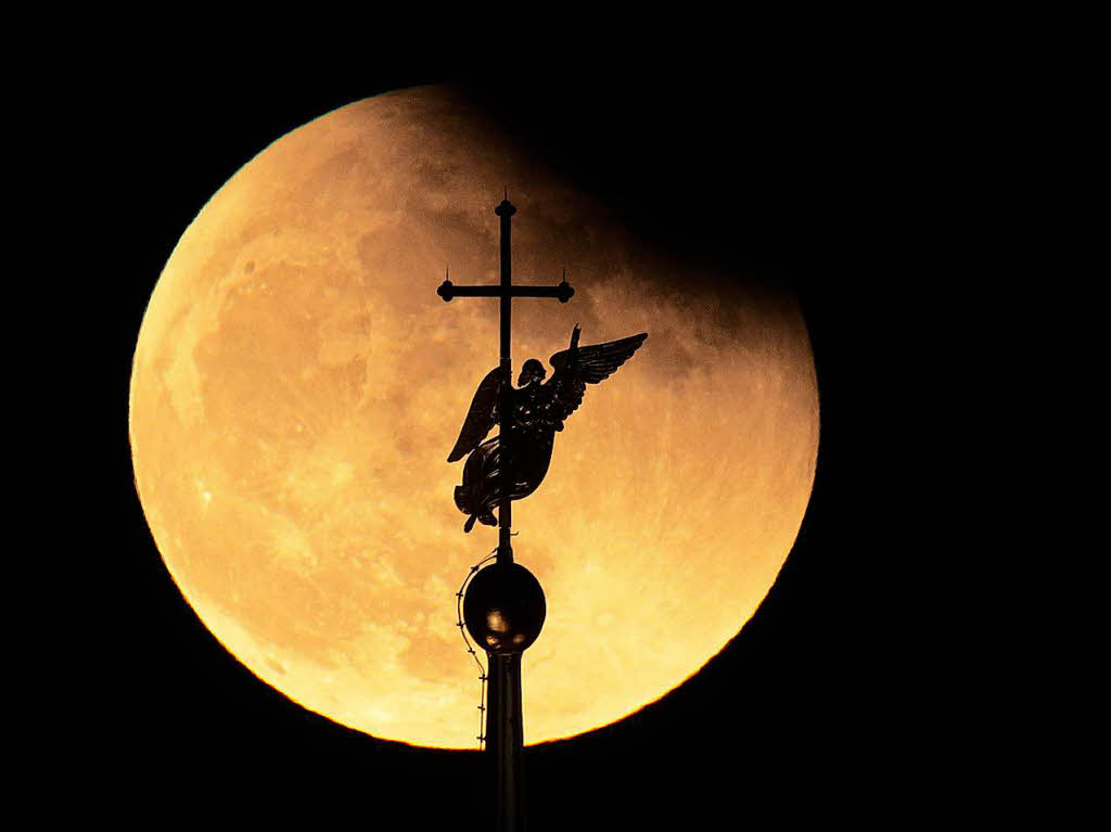 Russland, Sankt Petersburg: Der Engel am Kreuz auf dem Turm der St. Peter und Paul-Kathedrale zeichnet sich vor dem Mond ab, der teilweise vom Schatten der Erde bedeckt ist.