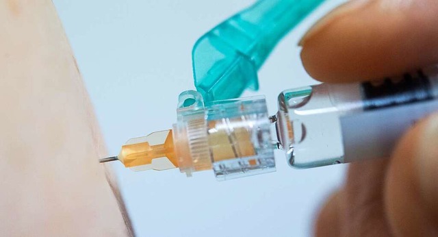 Ein Arzt impft eine Person gegen Grippe.  | Foto: dpa