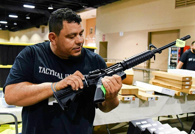 Ein Mann betrachtet bei einer Waffenmesse in Florida ein Gewehr.  | Foto: AFP