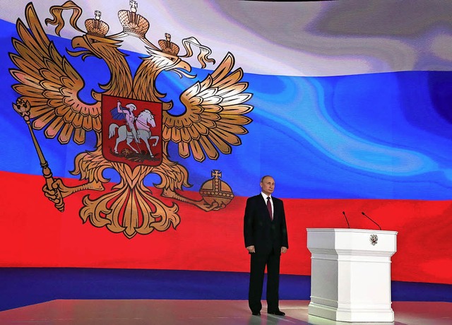 Prsident Wladimir Putin steht vor ein...en russischen Flagge mit Wappentier.    | Foto: DPA