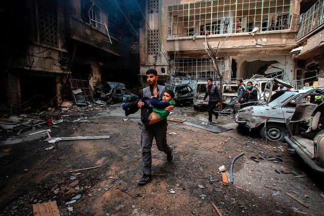 Ein Mann trgt nach einem Luftangriff ...ein Kind aus einem zerstrten Gebude.  | Foto: dpa