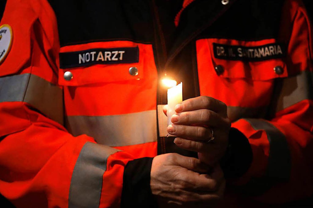 Ein Notarzt hält beim Gottesdienst für die Opfer in Münster eine Kerze.  | Foto: dpa
