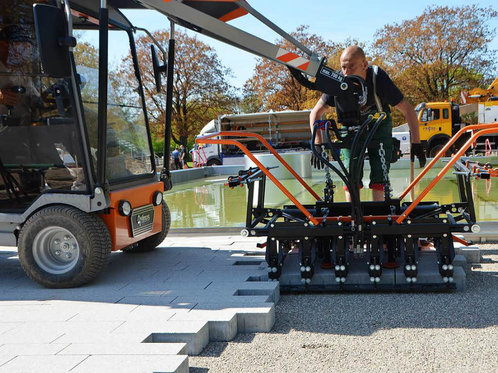 Eine Spezialmaschine setzt das Pflaster der Beckenumrandung gleich palettenweise.