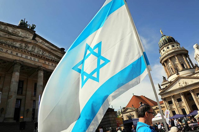 Mit einer Flagge von Israel nehmen Men...estag der Unabhngigkeit Israels teil.  | Foto: dpa
