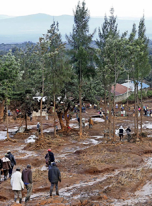 Kenia: Menschen waten durch die Schlammmassen.   | Foto: dpa