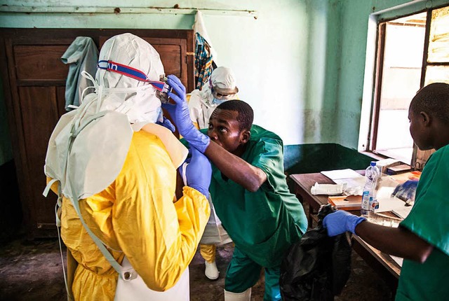 Mitarbeiter des Gesundheitswesens zieh...in der Isolationsabteilung behandeln.   | Foto: dpa
