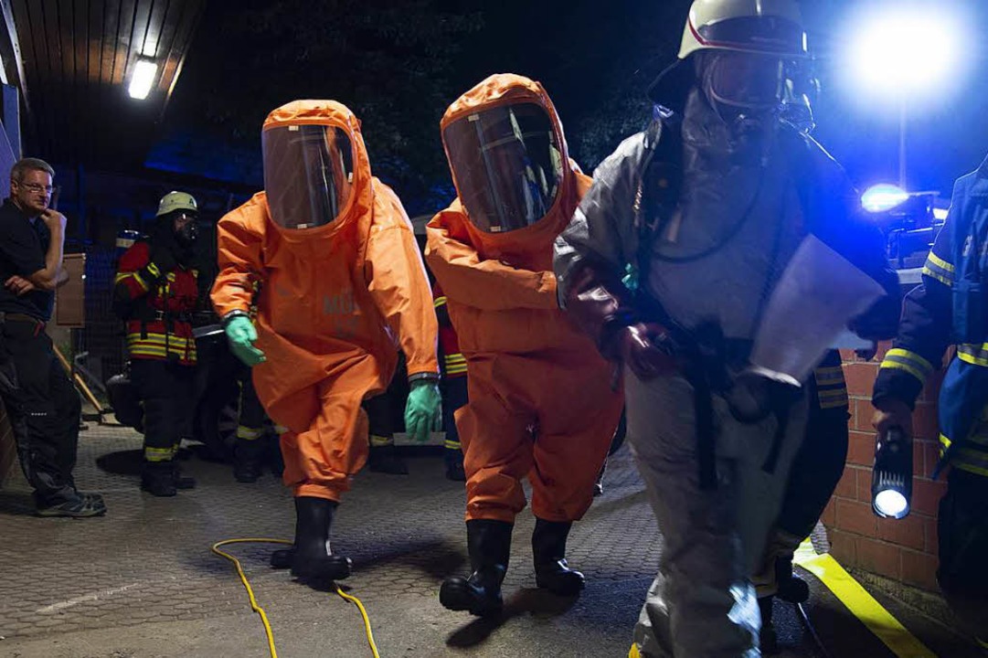 Das Gefahrgut-Team in Chemikalienschutzanzgen auf dem Weg zum Einsatzort.  | Foto: Volker Mnch
