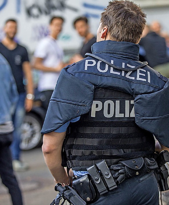 Ein Polizist bewacht eine Gruppe festgesetzter Männer.   | Foto: dpa