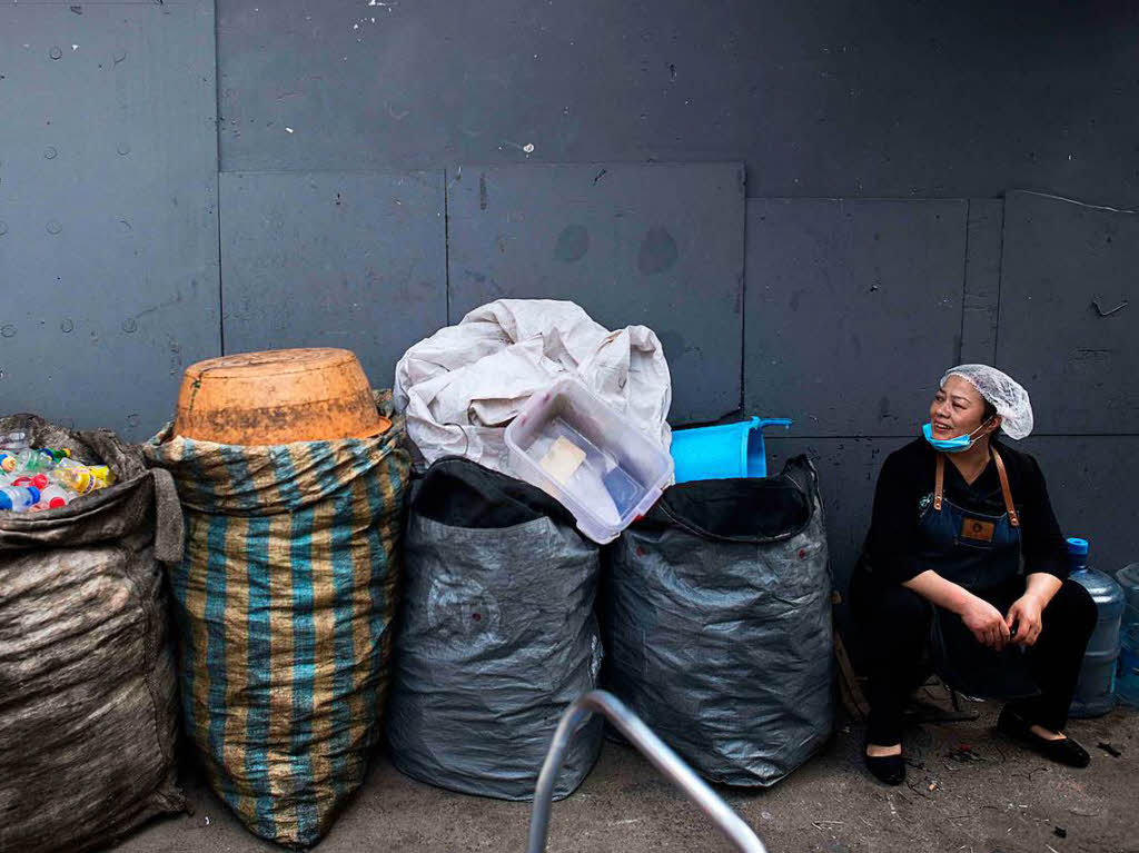 Eine Frau sitzt neben Scken mit Plastikflaschen bei einer Mllhalde in  in Beijing.