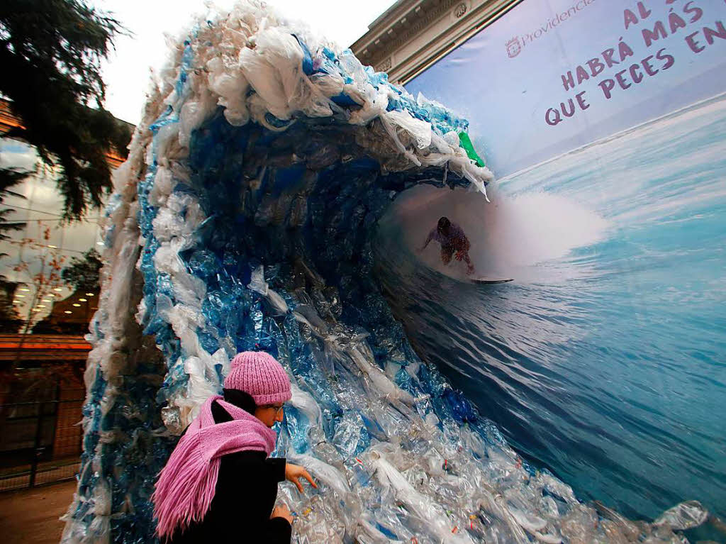 Diese Tafel zeigt einen Mann, der in einer Welle aus Plastik surft. Es soll auf die Verschmutzung der Meere in Santiago aufmerksam machen.