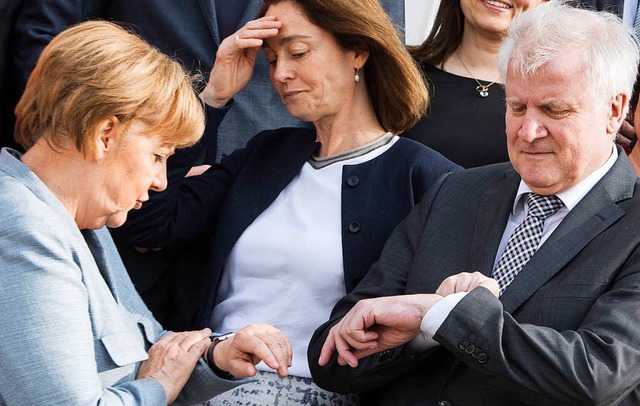 Bundeskanzlerin Angela Merkel  und Inn...hrend des Gruppenfotos auf ihre Uhren.  | Foto: dpa