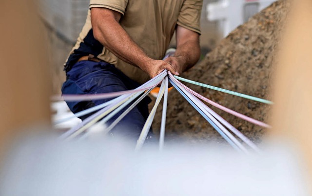Ein Mitarbeiter bndelt Glasfaser-Leerrohre fr schnelle Internetzugnge.   | Foto: dpa