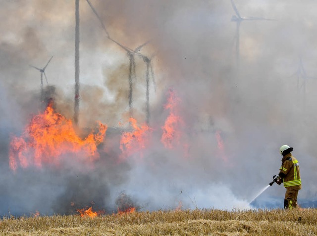 Ein Feuerwehrmann lscht ein brennendes Getreidefeld.  | Foto: dpa