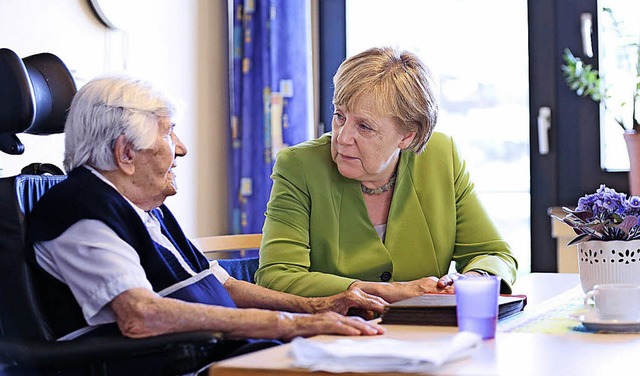 Angela Merkel (rechts) spricht mit einer Bewohnerin des Heims.  | Foto: dpa