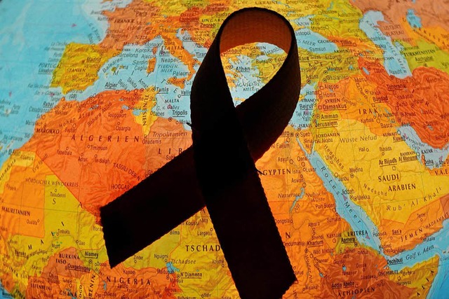 Eine rote Aids-Schleife liegt auf einem Globus   | Foto: dpa