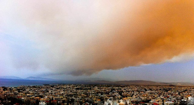 Eine Rauchwolke frbt Teile des Himmels ber Athen orange.  | Foto: dpa
