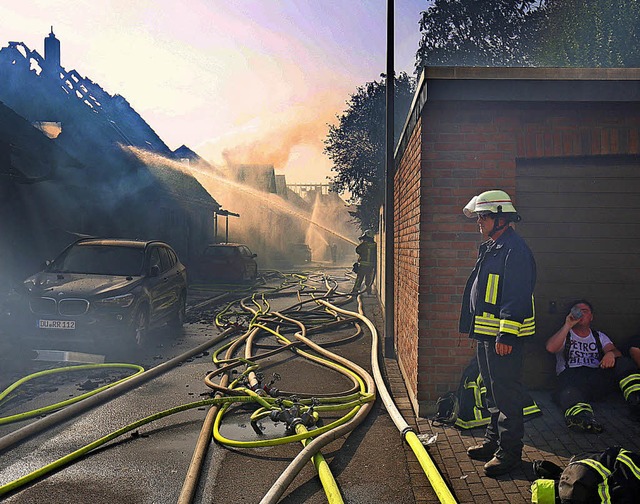 Erschpfte Feuerwehrleute machen beim Grobrand in Siegburg eine Trinkpause.   | Foto: dpa