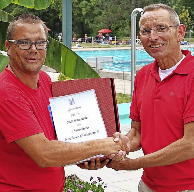 Bademeister Manuel Gutmann (links) gra...00. Freibadbesucher in dieser Saison.   | Foto: Hans-Jrgen Hege