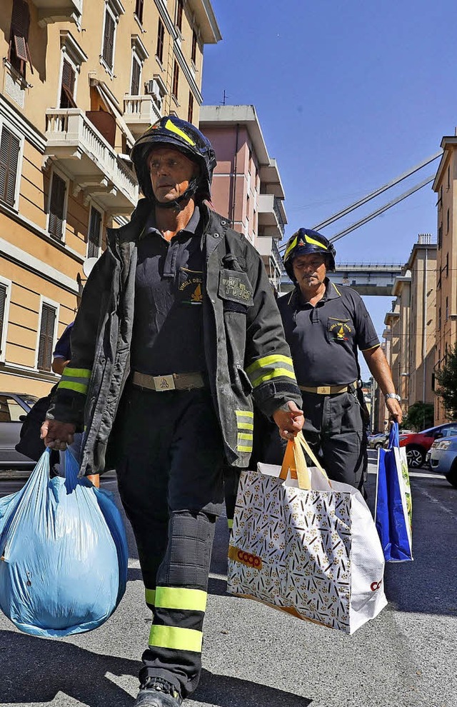 Feuerwehrmnner tragen das Hab und Gut...die diese nicht mehr betreten drfen.   | Foto: dpa