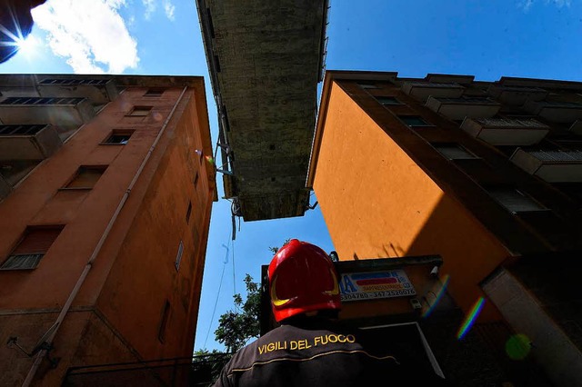 Ein Feuerwehrmann schaut auf die Reste...ber evakuierte Wohnhuser hinausragt.  | Foto: dpa