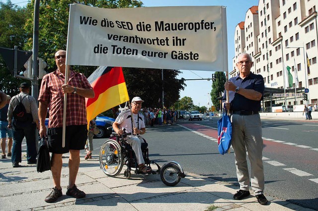 Ein Plakat und eine Fahne als Protest ...n Besuch von Angela Merkel in Dresden   | Foto: DPA