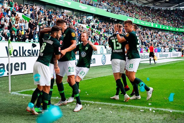 Die Wolfsburger bejubeln ihren 2:1-Einstandsieg.  | Foto: dpa