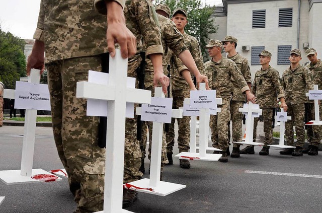 Ukrainische Soldaten tragen Kreuze von...ten in der Ostukraine gettet wurden.   | Foto: DPA