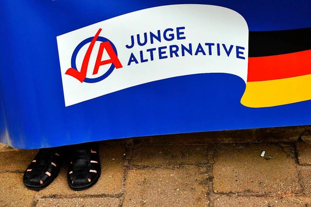 Ein Mann in schwarzen Sandalen hlt ei...pfauftritt von Bundeskanzlerin Merkel.  | Foto: dpa