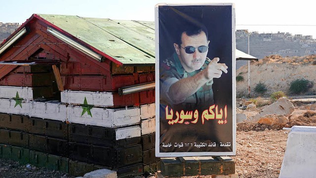 Syrien: Ein Postenhuschen an der Brc...m Bild von Prsident Baschar al-Assad.  | Foto: dpa