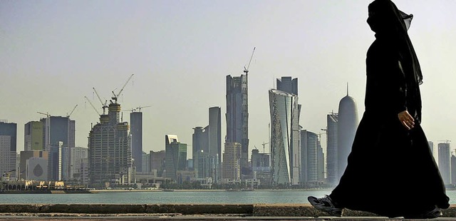 Eine Frau spaziert vor der Skyline der Stadt Doha in Katar.   | Foto: DPA