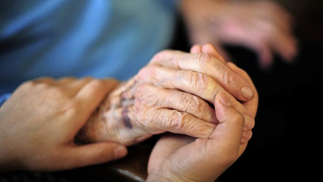 Eine Person hlt die Hand einer Patien...patienten sollen davon nichts merken.   | Foto: Symbolfoto: Daniel Reinhardt, DPA
