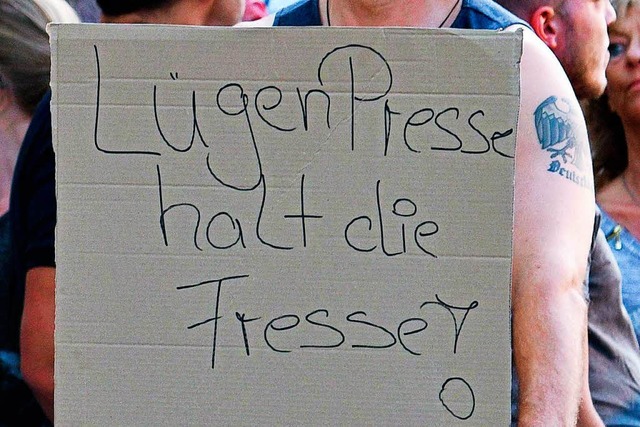 Ein Teilnehmer einer Kundgebung rechte... August  dieses Plakat in den Hnden.   | Foto: dpa