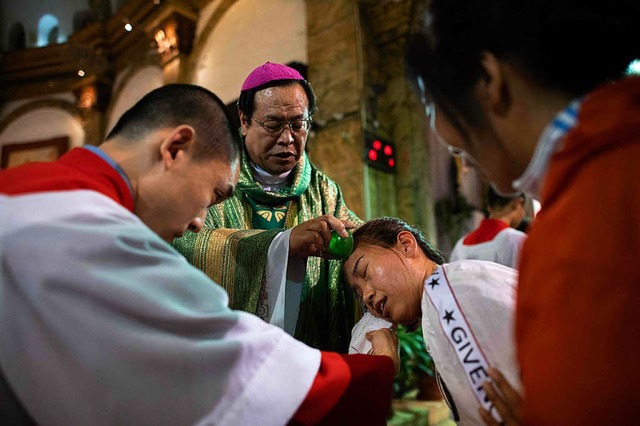 Bischof Joseph Li Shan (Mitte) tauft eine Frau whrend einer Messe in Peking.  | Foto: AFP