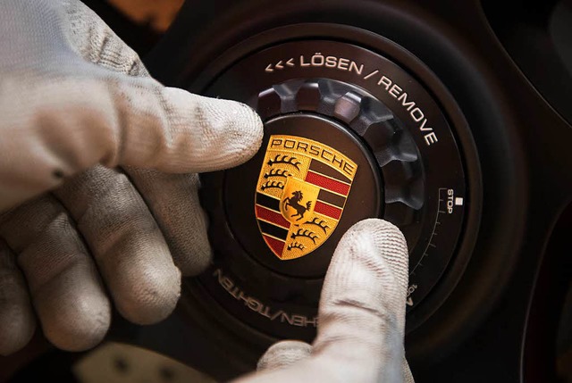 Ein Mitarbeiter der Porsche AG montier...ammwerk ein Logo an einem Porsche 911.  | Foto: dpa