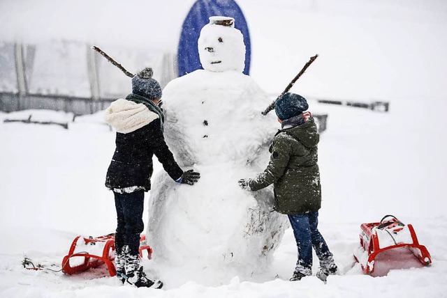 Robert und Eline aus Belgien bauen einen Schneemann auf dem Feldberg.  | Foto: dpa