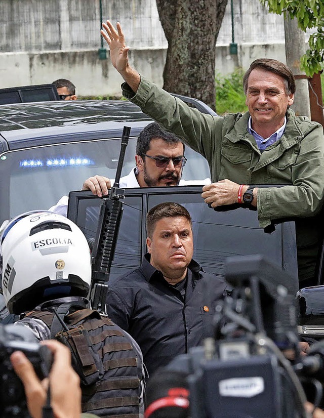 Siegesgewiss  winkt  Jair Bolsonaro bei der Fahrt zum Wahllokal.   | Foto: dpa