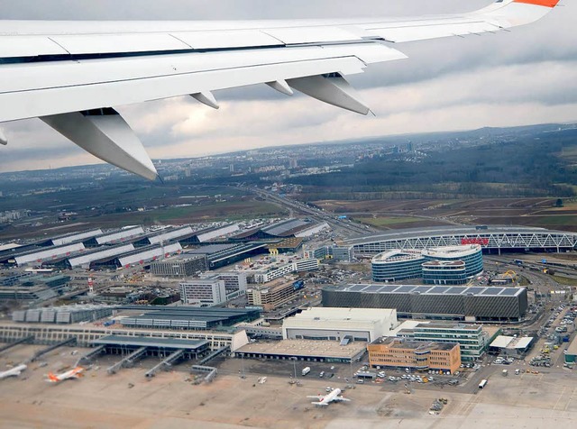 Reisende am Flughafen in Stuttgart ms... Hintergrund ist ein Feuerwehreinsatz.  | Foto: dpa